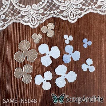 Assorted white and clear acrylic flower embellishments on wooden background