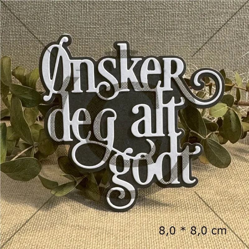Svart og hvit dekorativ skilt med norsk tekst omgitt av grønn lauv